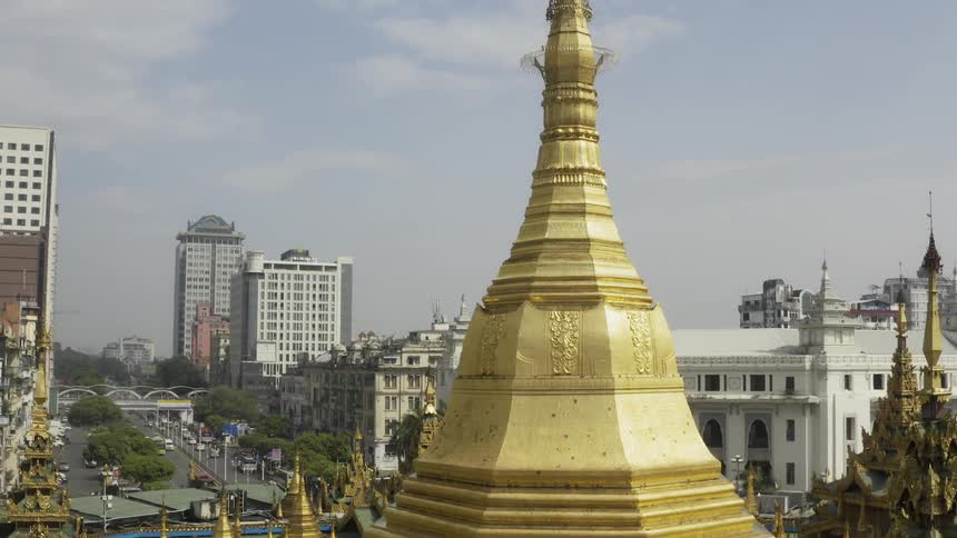 An elaborate golden dome of a shrine stands out amidst the neighboring buildings in a large city