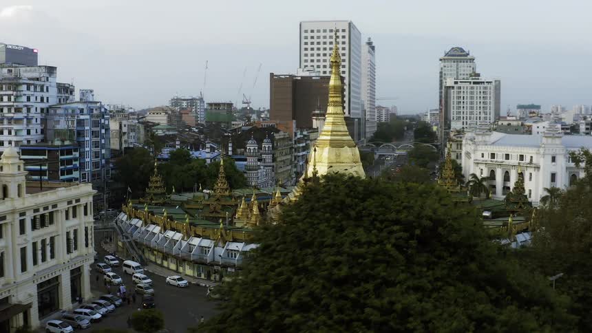 Cars in a city travel around a stupa and buddhist temple and pagodas