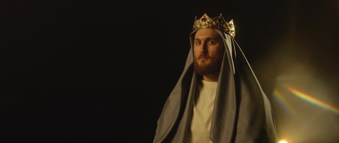 A king stands in a dark room