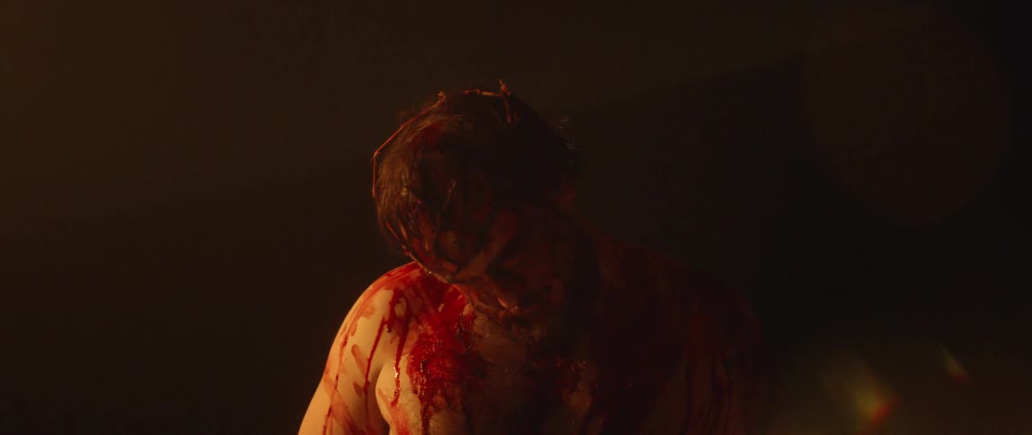 A bloody caucasian man wearing a crown of thrones dropping his head