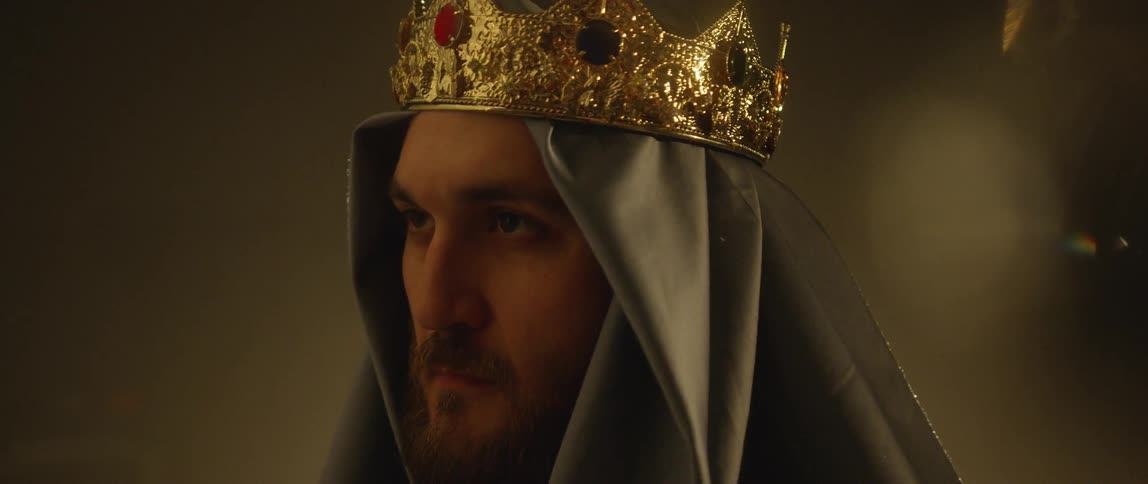 A man in a hood and crown raising his head