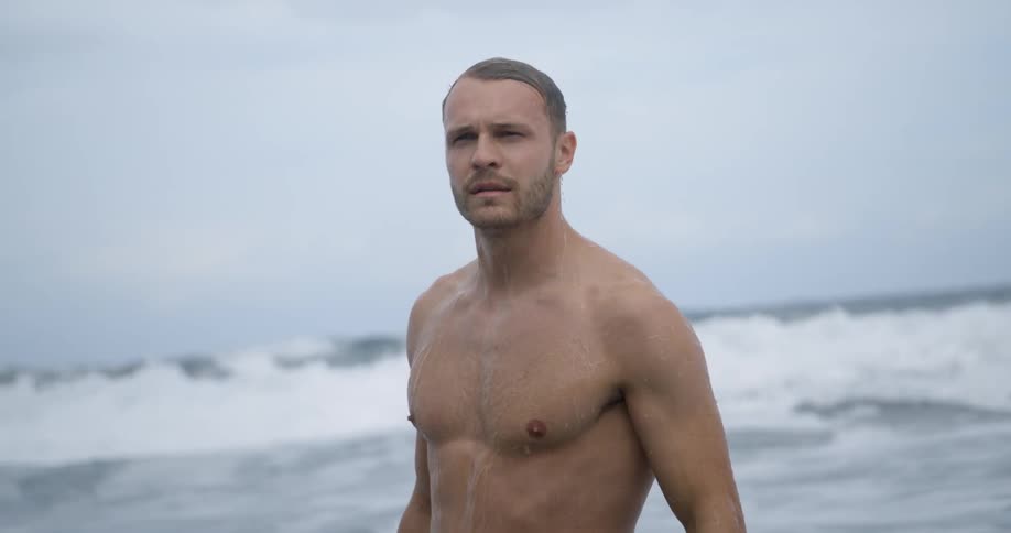 Man wipes dripping hair as he wades out of sea