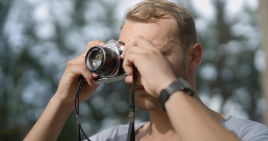 Man in forest taking a picture with a camera