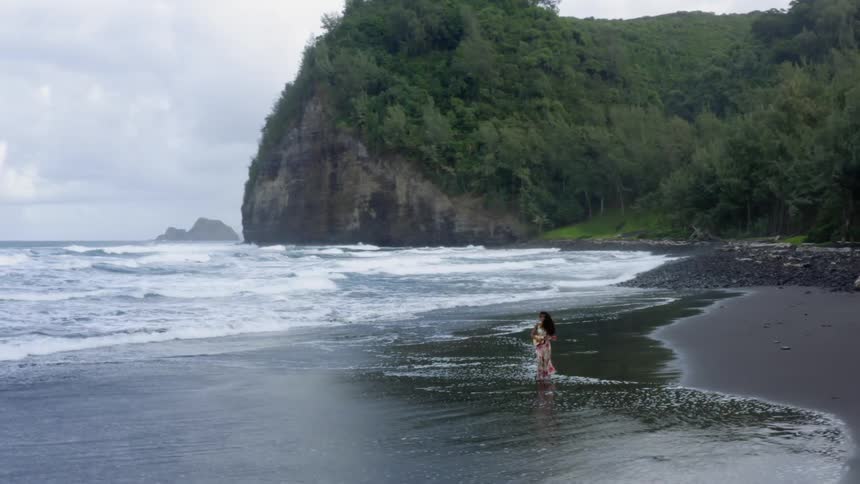 A woman in a floral dress walking on the beach