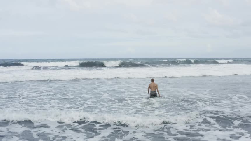 A man is walking into the ocean