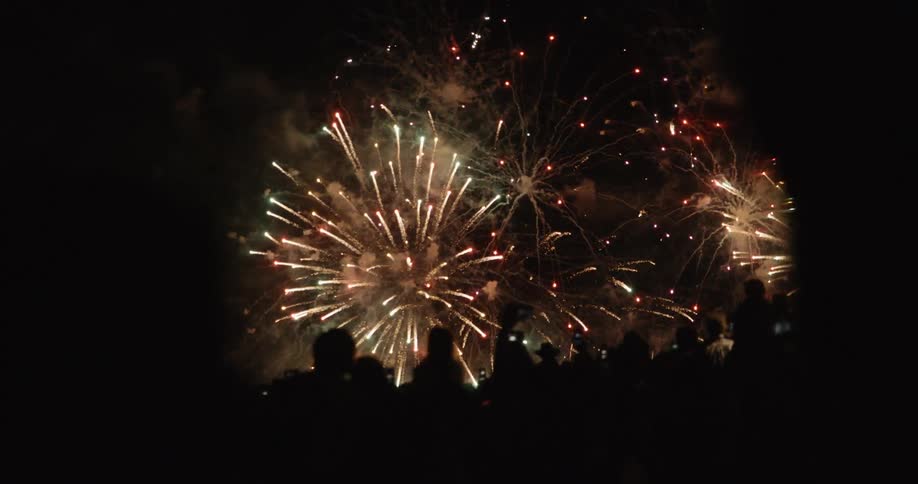 Fireworks explode in night sky over crowd