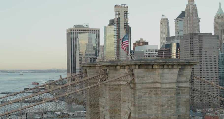 A bridge with the american flag on top with buildings in the background
