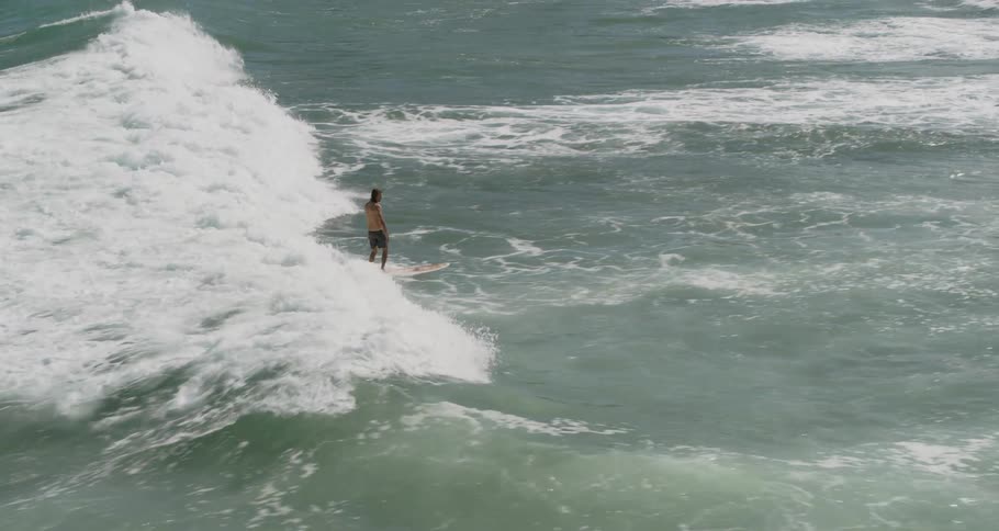 Man surfs wave during daylight