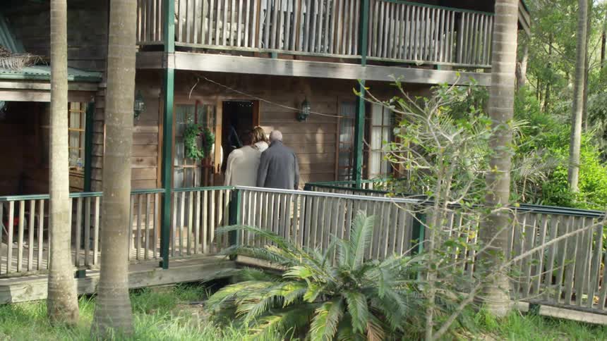 A group of people walk into a wooden house