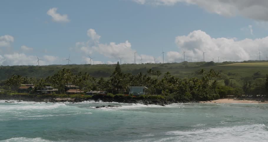 Ocean waves wash towards a beautiful coastal area that is lined with beaches and trees