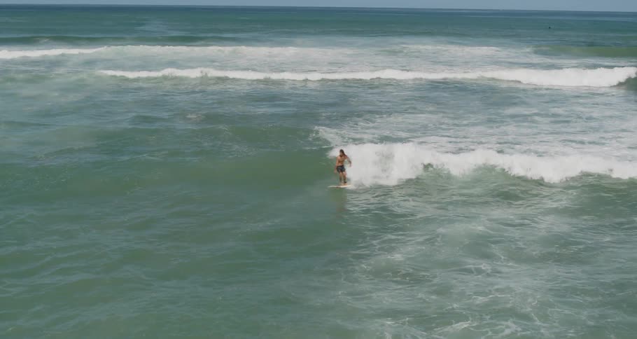 Long hair man surfs wave in the daytime