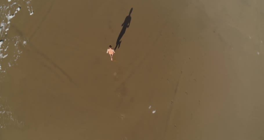 Birds eye view of a runner running on the sand alongside the shoreline