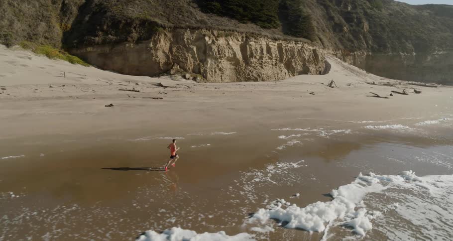 Man runs on the wet sand beach next to the ocean