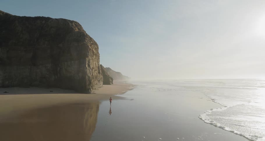 A man running on the beach with the sky in the background