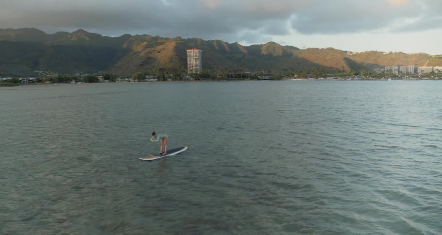 A woman is doing yoga on a paddleboard in the ocean
