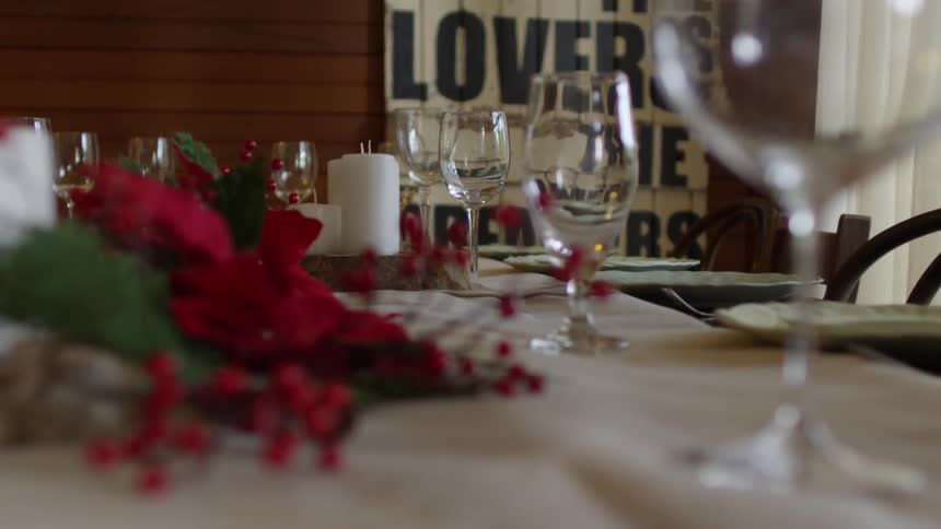 A woman adds candles to a table decorated for the holidays