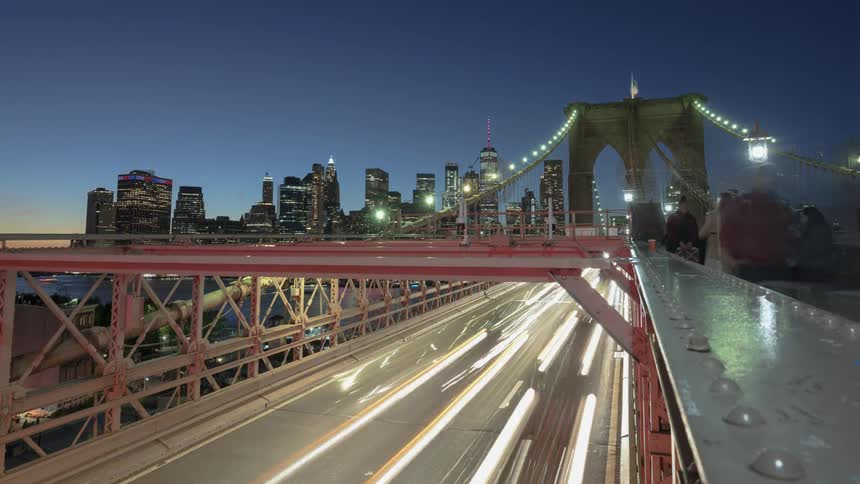 People walk along the top of a bridge as traffic flows by beneath them