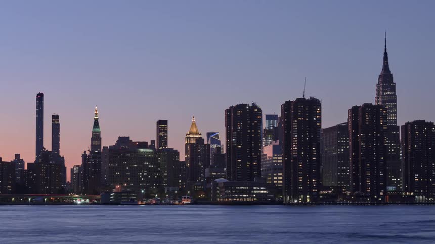 Large and small boats pass a city skyline