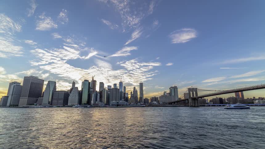Boats leave wakes across water speeding past city