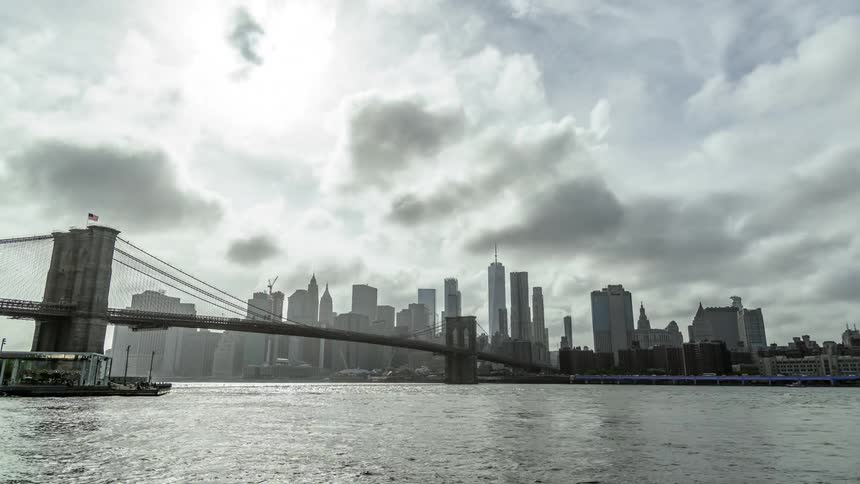A downtown city sits next to a river with a suspension bridge