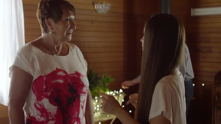 An older woman and a younger woman speak at a family christmas gathering