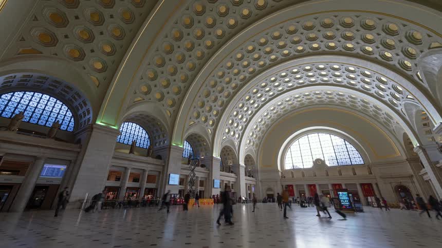 Pedestrians walk through a large train station