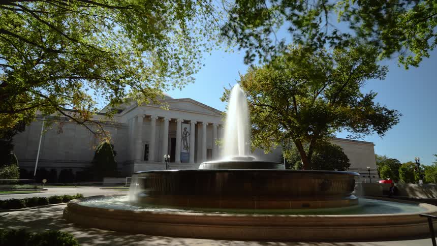 A fountain sits in a park in a city