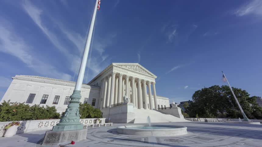 Pedestrians walk through supreme court building and the associated plaza