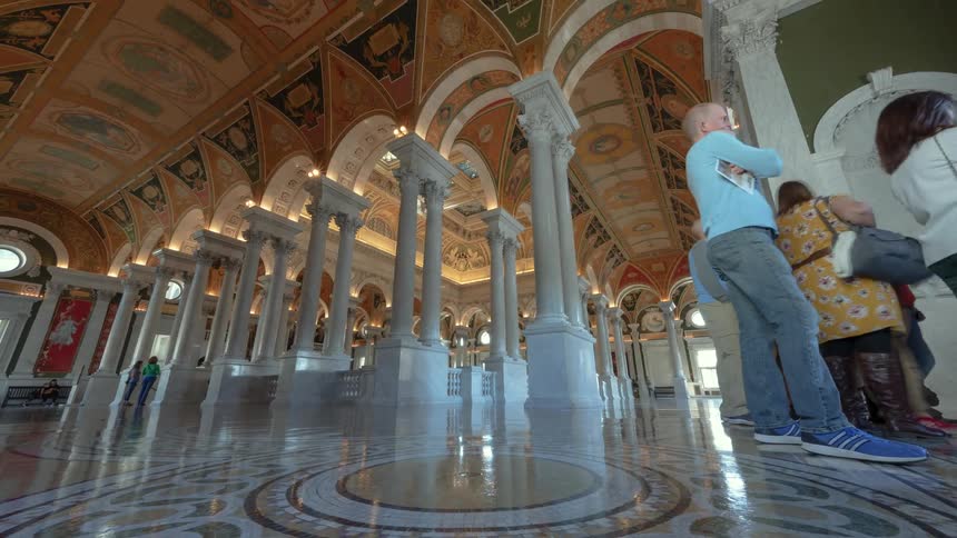 People walk around inside an ornate building