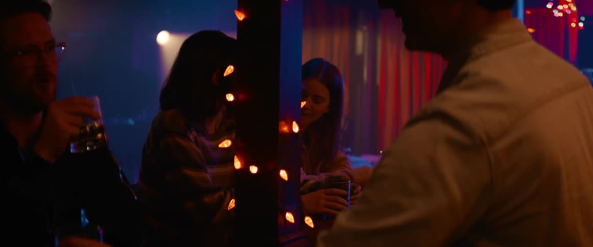 A few people sit at a bar top together with drinks in front of them