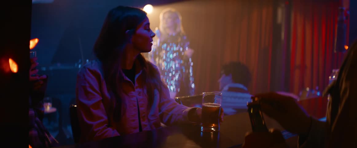 Woman sits at bar while singer performs on stage