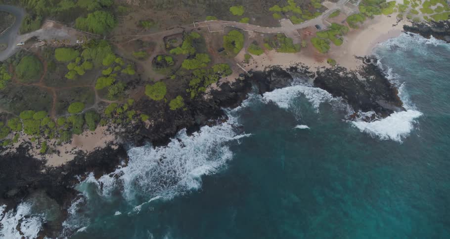 Ocean waves splash against the rocky shore and beach sand