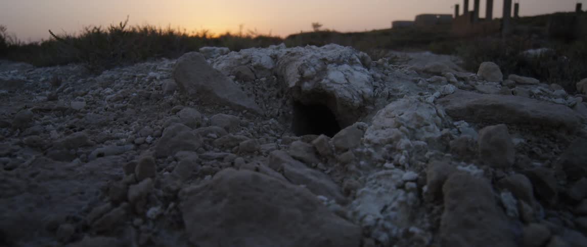A moving shot of rocks in front of a sunset