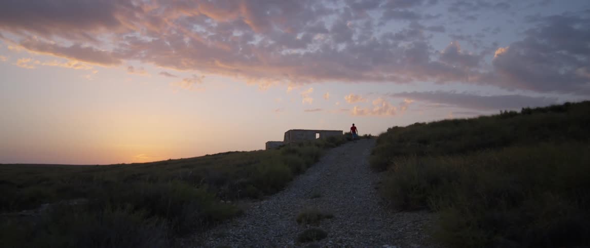 A man walking up a dirt path at dusk