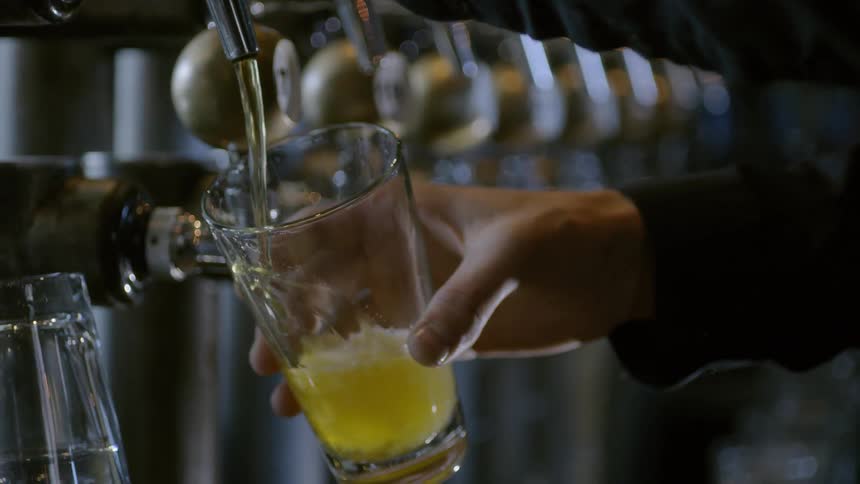 Person fills beer glass from one of a series of spouts