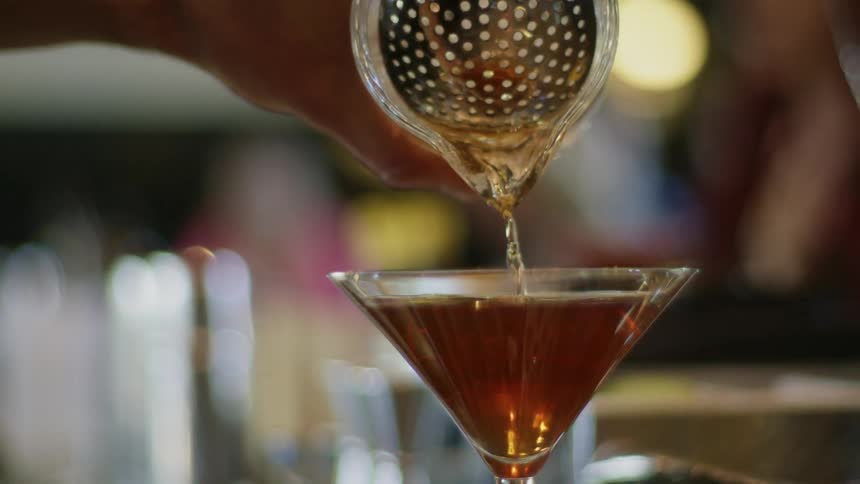 A bartender is pouring alcohol into a glass
