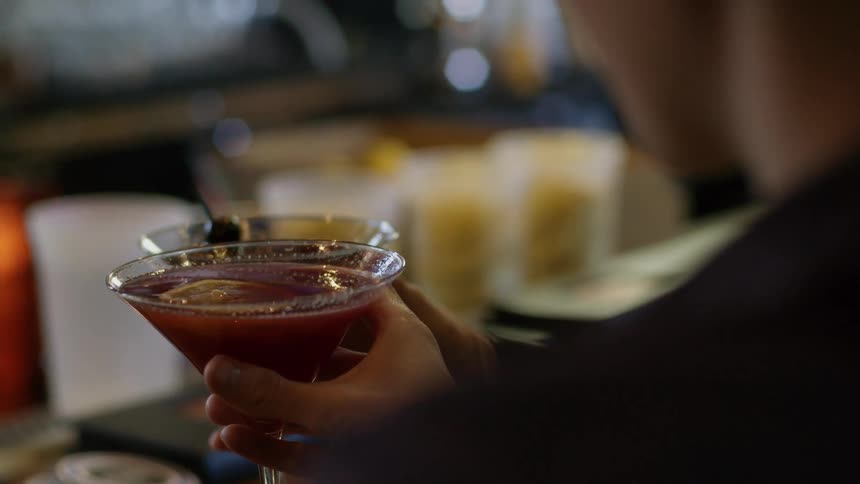 Two people clinking martini glasses together in a bar