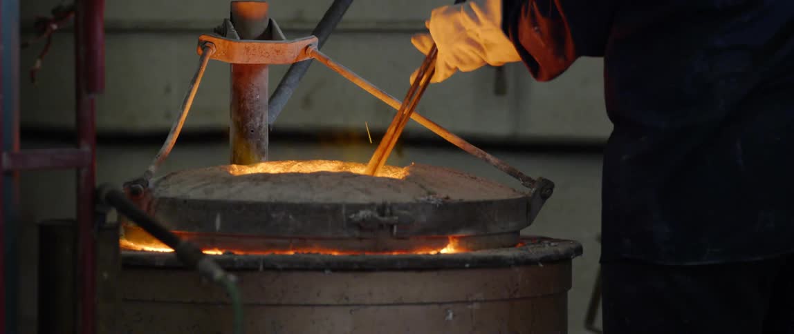 A person puts a brick of metal into a furnace