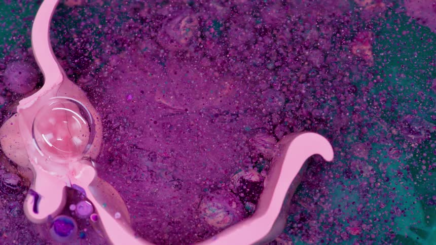 Pink solid circle expanding among colored particles floating in liquid
