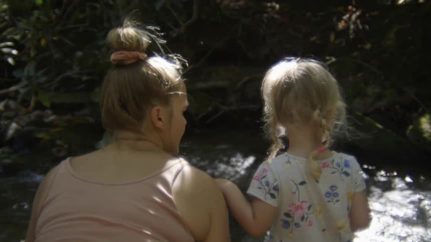 Mother and daughter are outside by a river