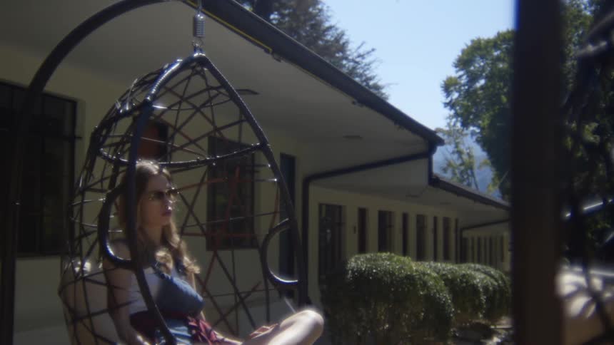 A woman sitting on a patio swing during the day