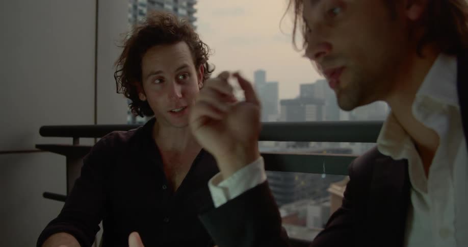 Two men discuss project with city view as a backdrop