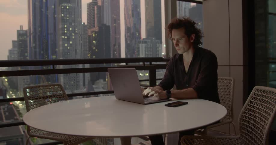 A man sitting at a table typing on a laptop