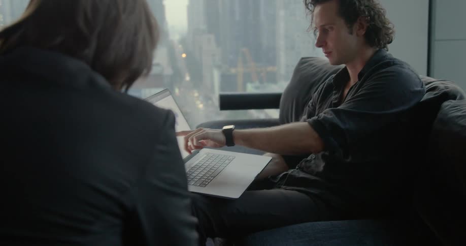 Men have discussion referencing laptop data near large windows