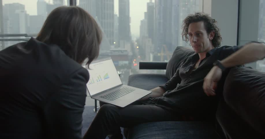 Two men work on a laptop in an office