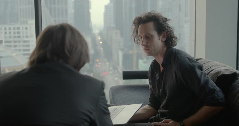 Two people talk while looking at a laptop