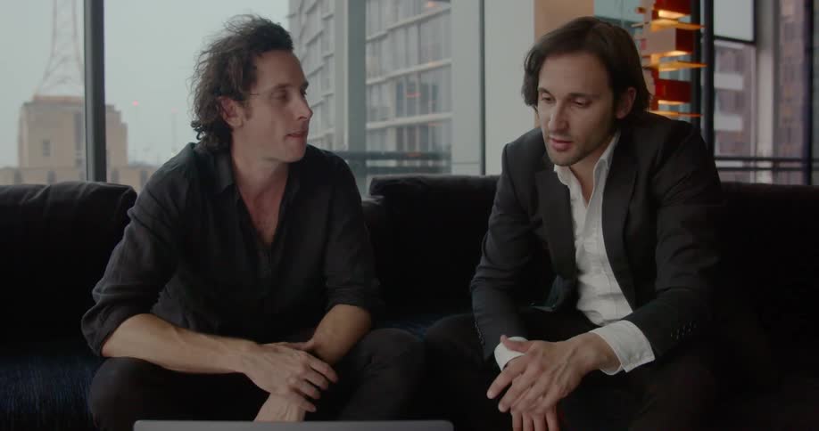 Two men discuss on a couch