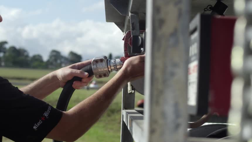 A man removes a gas nozzle at a pump station