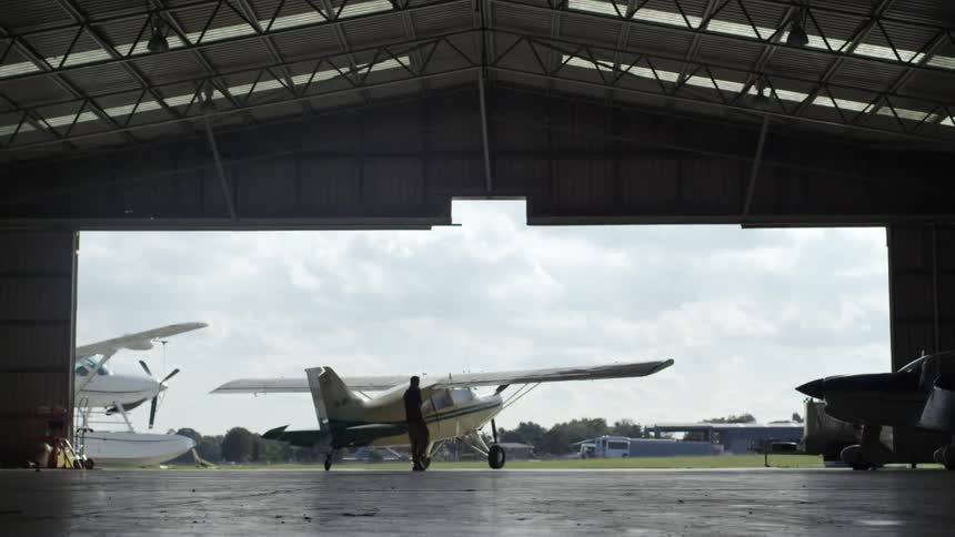 A man is walking in a airport hangar on a cloudy day