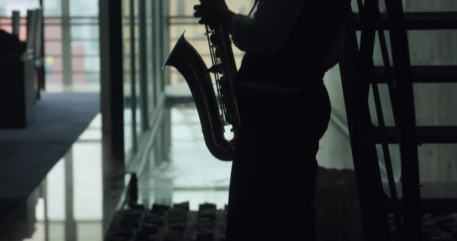 A man is playing the saxophone in the dark